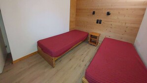Un alojamiento pequeño y de una sola habitación con dos camas individuales, una pared de madera y una mesita de noche de madera.