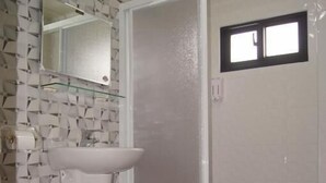 A bathroom with a white sink, a toilet, and a shower area. - Shimmer B&B (Magong)