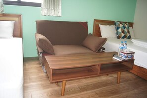 A room with a bed, a brown armchair, a wooden coffee table, and a small table with a box and bottles. - Shimmer B&B (Magong)