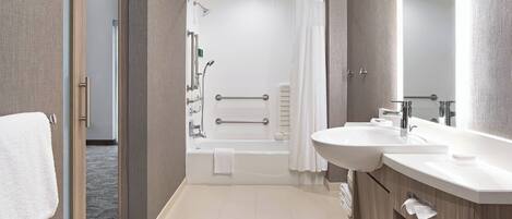 A modern bathroom with a bathtub, shower, and dual sinks.