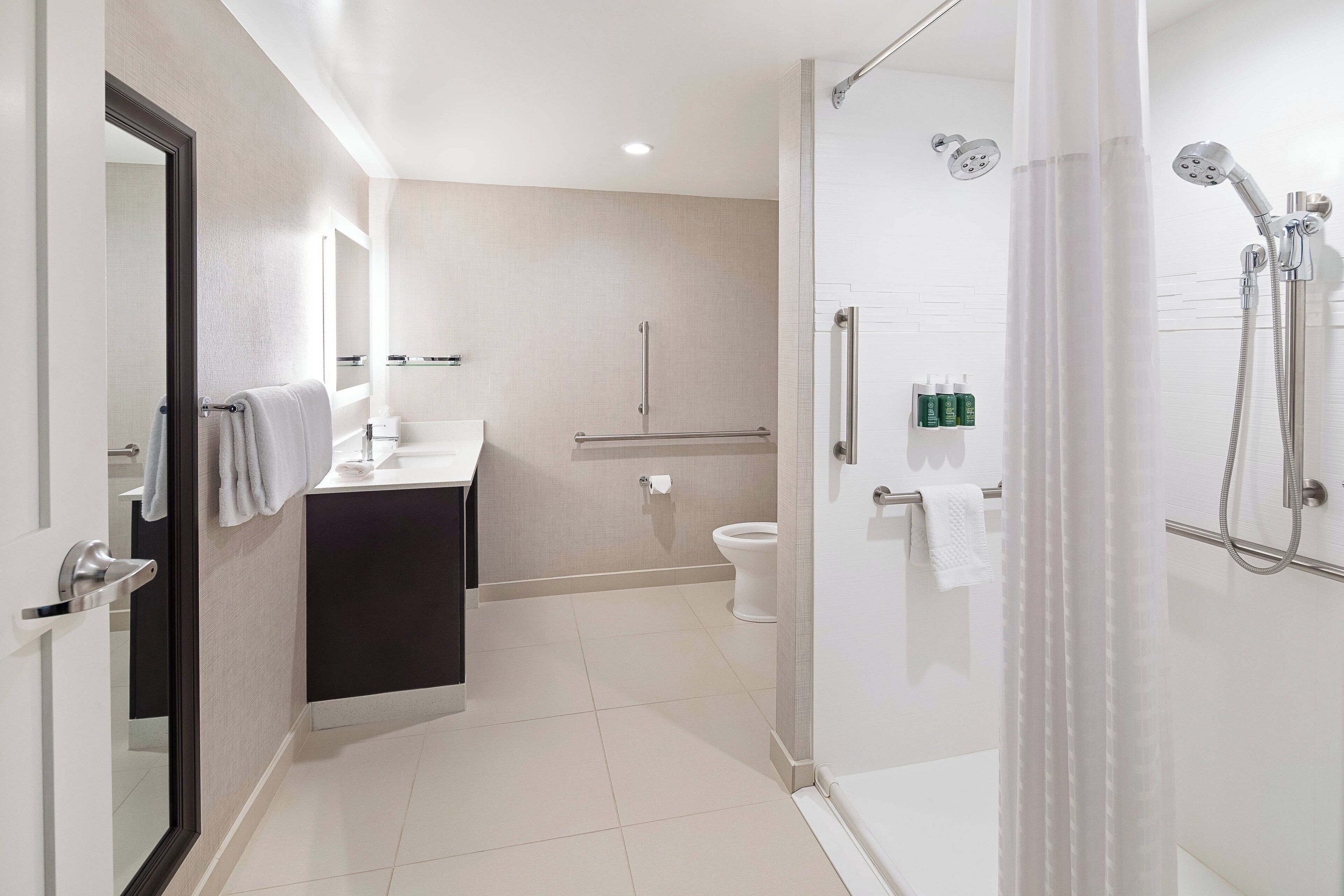 A modern bathroom with a glass shower enclosure, a toilet, and a sink with a towel rack.