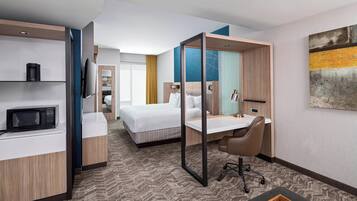 Ein Hotelzimmer mit Bett, Schreibtisch, Stuhl, Mikrowelle und Fernseher.
