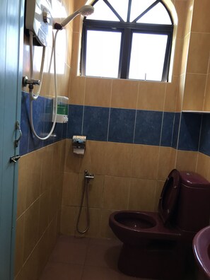 A small bathroom with a toilet, a shower, and a window. - Kangsar Hotel (Kuala Kangsar)