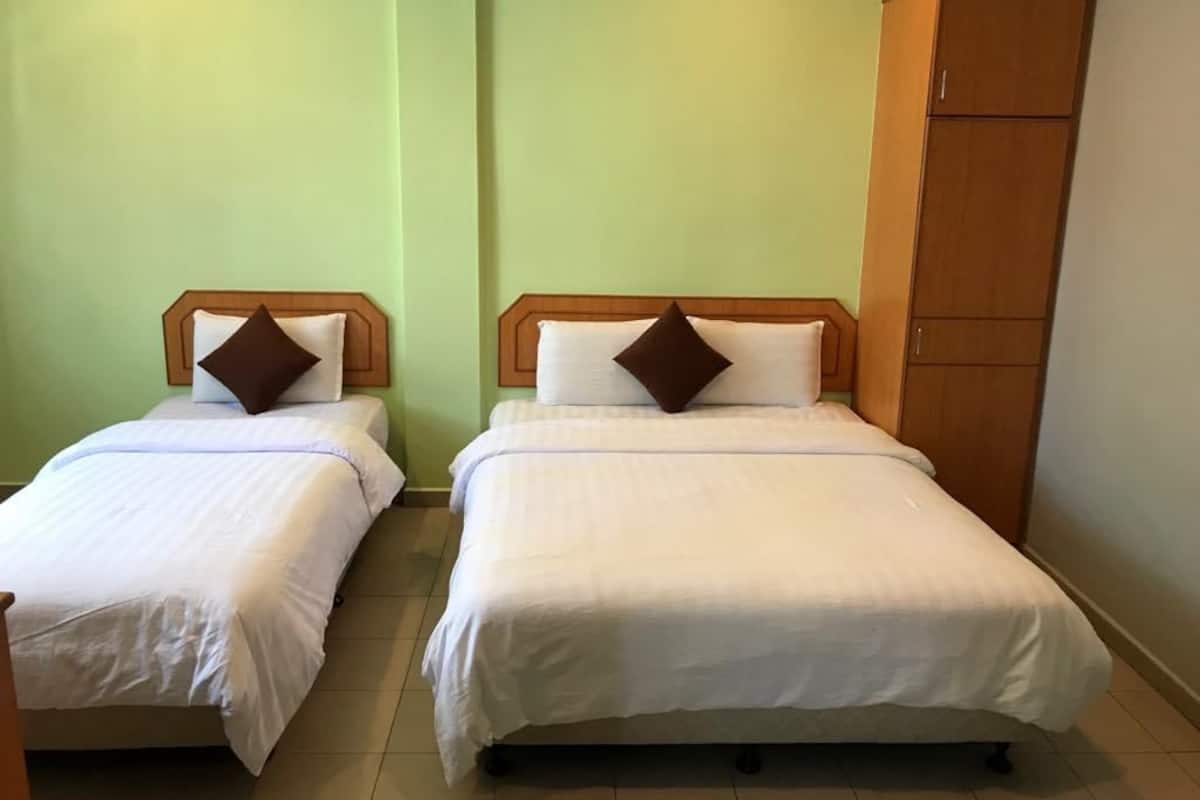 Dos camas individuales con cabeceros de madera y ropa de cama blanca, un armario de madera y paredes de color verde claro.