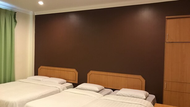 Una habitación de hotel con dos camas individuales, un armario de madera y una cortina verde.