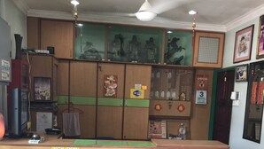 Un mostrador de recepción con un buzón de llaves, un ventilador de techo y diversas decoraciones, incluyendo un calendario y un cuadro enmarcado.