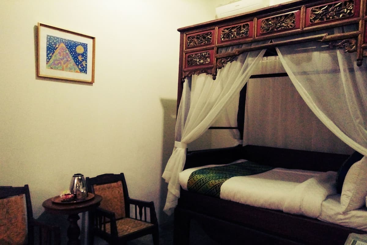 A bedroom with a bed, a nightstand, a chair, and a small table.