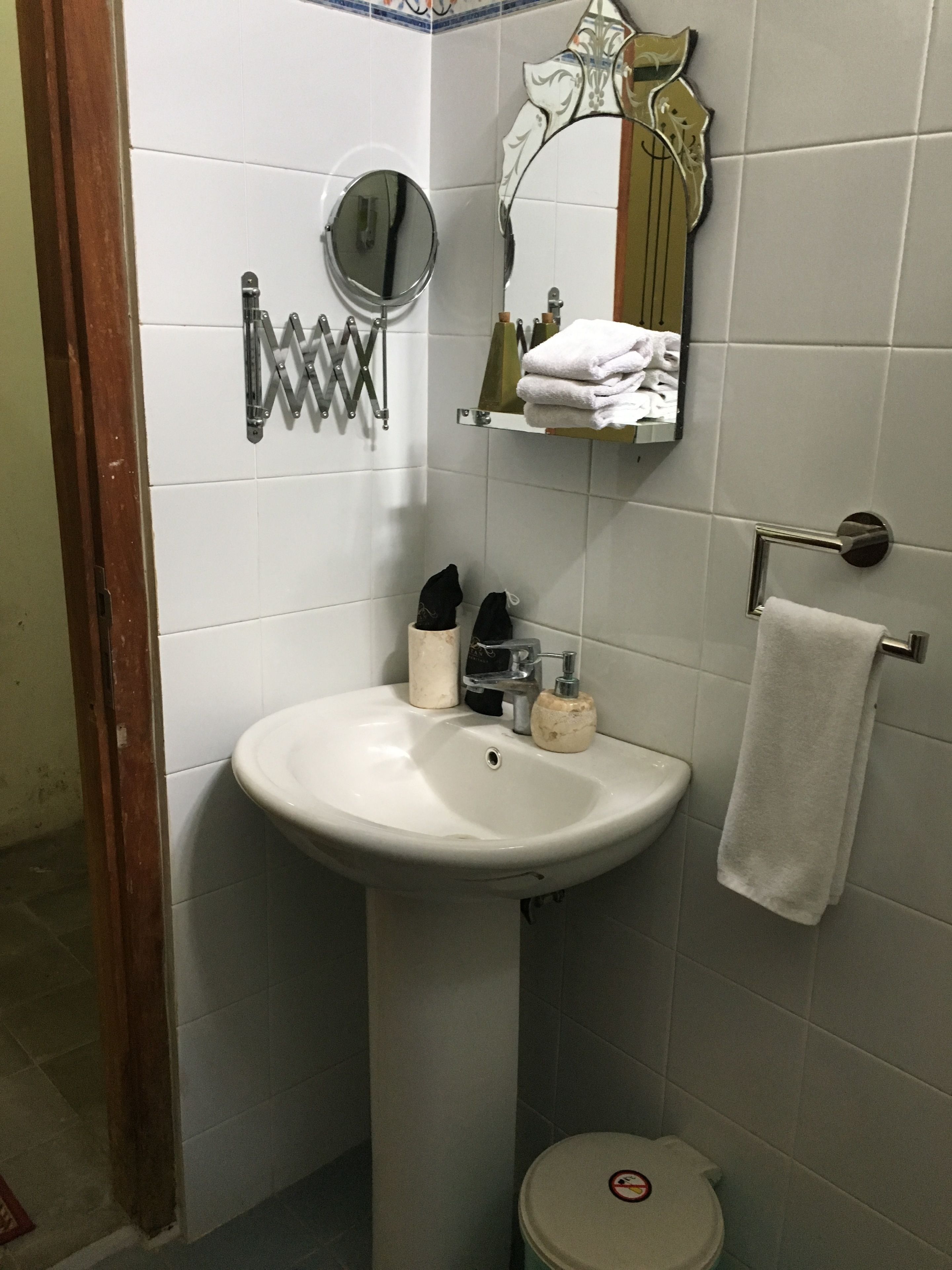 A bathroom with a white sink, a mirror, a towel rack, and a toilet.