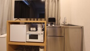 A compact kitchenette with a microwave, coffee maker, and a refrigerator. - JUSTIN FUKUOKA (Fukuoka)