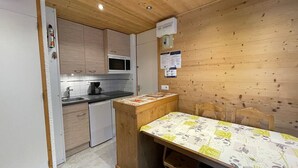 Uma cozinha compacta com armários de madeira, micro-ondas, cafeteira e um refrigerador pequeno.