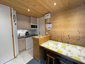 Eine kompakte Küche mit Holzausstattung, einer Mikrowelle, einer Kaffeemaschine und einem kleinen Kühlschrank.