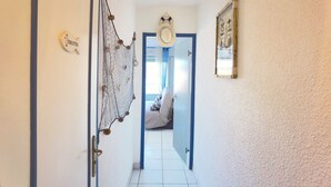 A hallway with a sign indicating the direction to the toilets, a decorative net hanging on the wall, and a door leading to a room with a bed and a window. - Cozy Appart 150 m from the beach with balcony + Parking (Biscarrosse)
