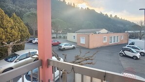 Ein Parkplatz mit mehreren Autos, ein Gebäude mit flachem Dach und eine Bergkulisse im Hintergrund.