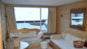 A cozy room with a wooden bed, a small table, and a window with curtains.