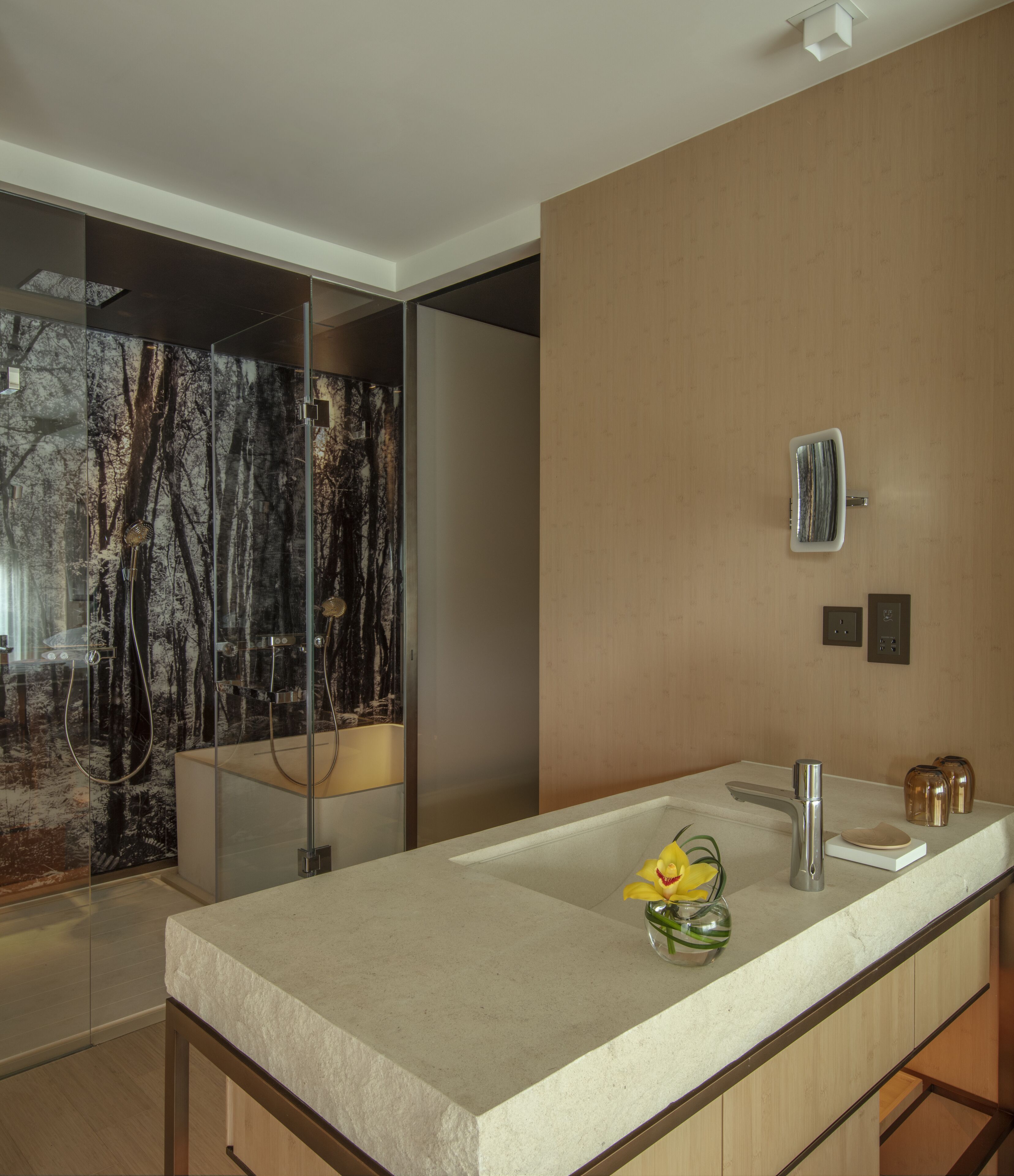 A modern bathroom with a large mirror, a sink, and a shower area with a glass door.