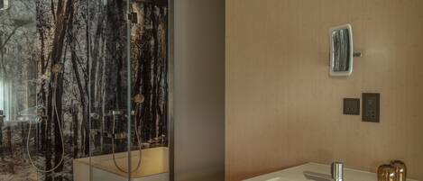 A modern bathroom with a large mirror, a sink, and a shower area with a glass door.