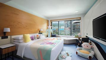 Ein Hotelzimmer mit einem großen Bett, einem Fernseher, einem Fenster mit Blick auf die Stadt und weichen Plüschfiguren auf dem Boden.