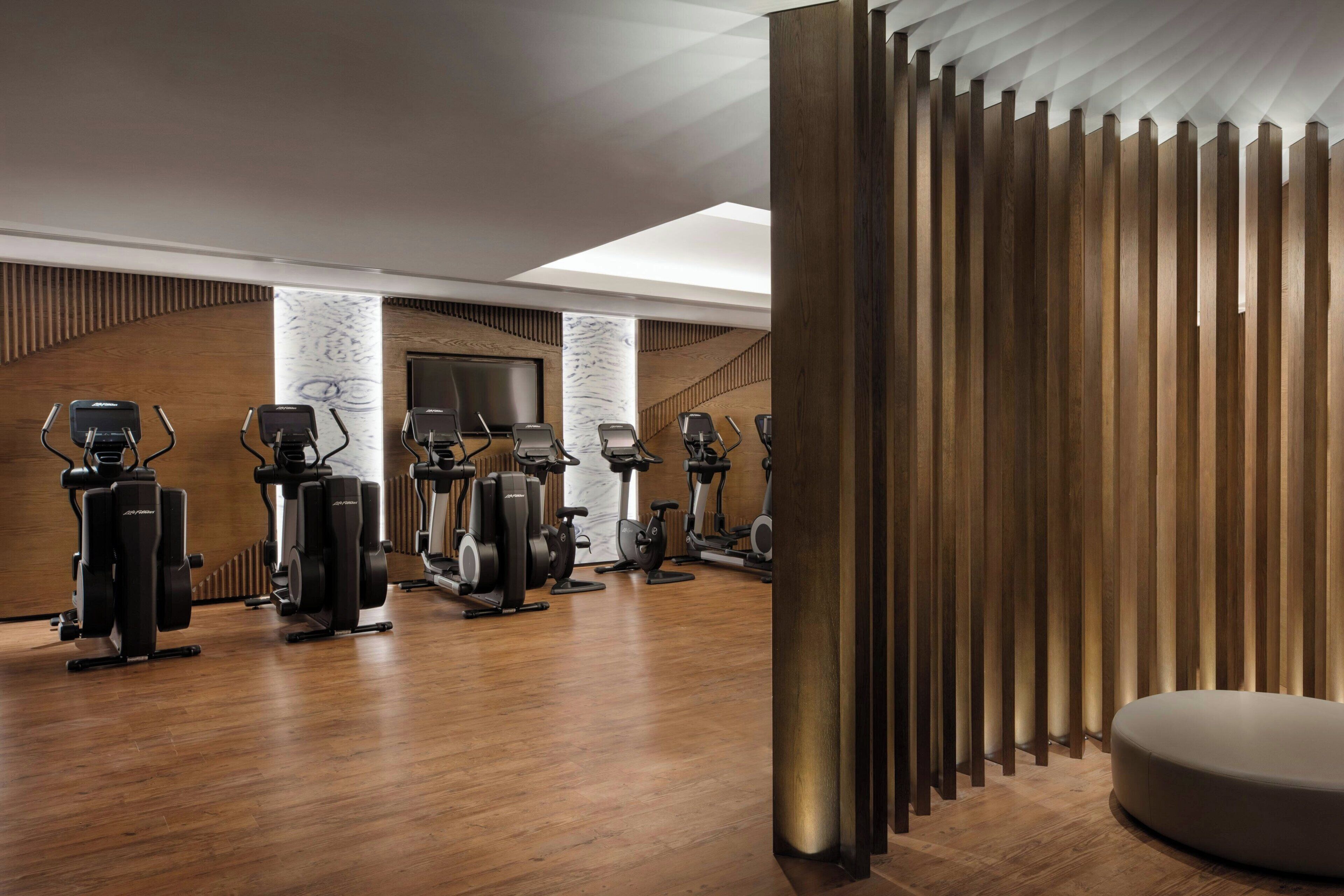 A gym with stationary bikes, elliptical machines, and a large mirror.