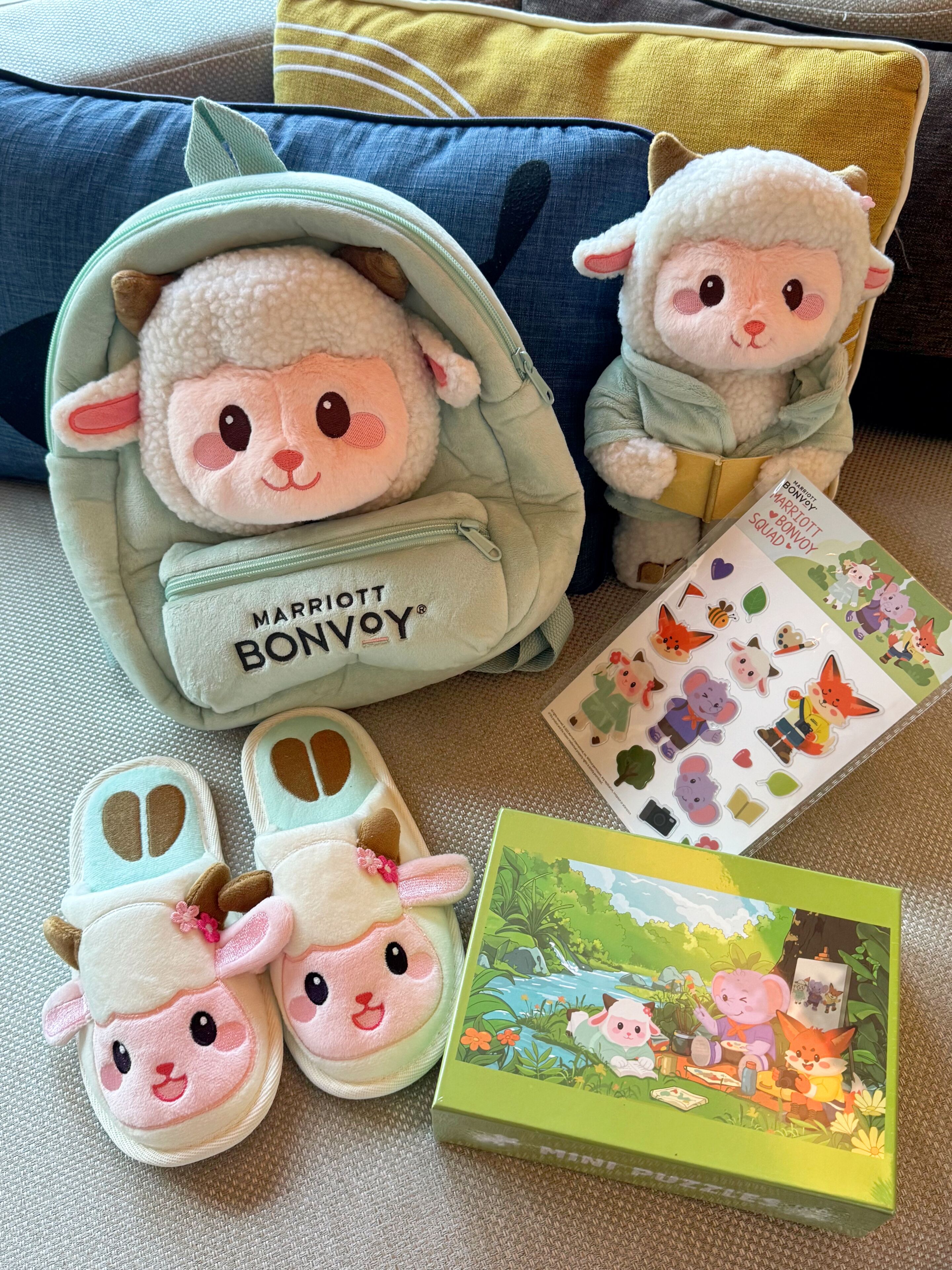 Um brinquedo de pelúcia dentro de uma bolsa verde com a inscrição 'Marriott Bonvoy', um par de chinelos e uma caixa de quebra-cabeça.