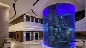 A modern lobby with a large aquarium, curved architecture, and a reception desk. - Hong Kong Ocean Park Marriott Hotel (Hong Kong)