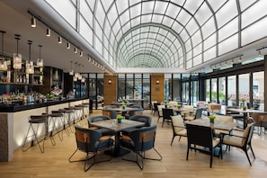 A spacious indoor area with a high ceiling and a glass dome structure. There are tables and chairs arranged for dining, and a bar area with bottles and glasses. - Hong Kong Ocean Park Marriott Hotel (Hong Kong)