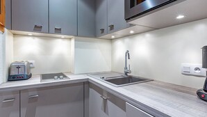 A modern kitchen with grey cabinets, a stainless steel sink, a toaster, and a built-in oven. - Valmorel - Cozy apartment for 4, direct access to slopes (Valmorel)