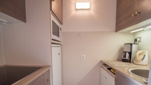 Eine kleine Küche mit Mikrowelle, Kaffeemaschine und Geschirrspüler.