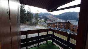A balcony with a view of a mountain and a building. - Family Apartment with Balcony, Ski Access, Upgraded Kitchen & Washer (Valmorel)
