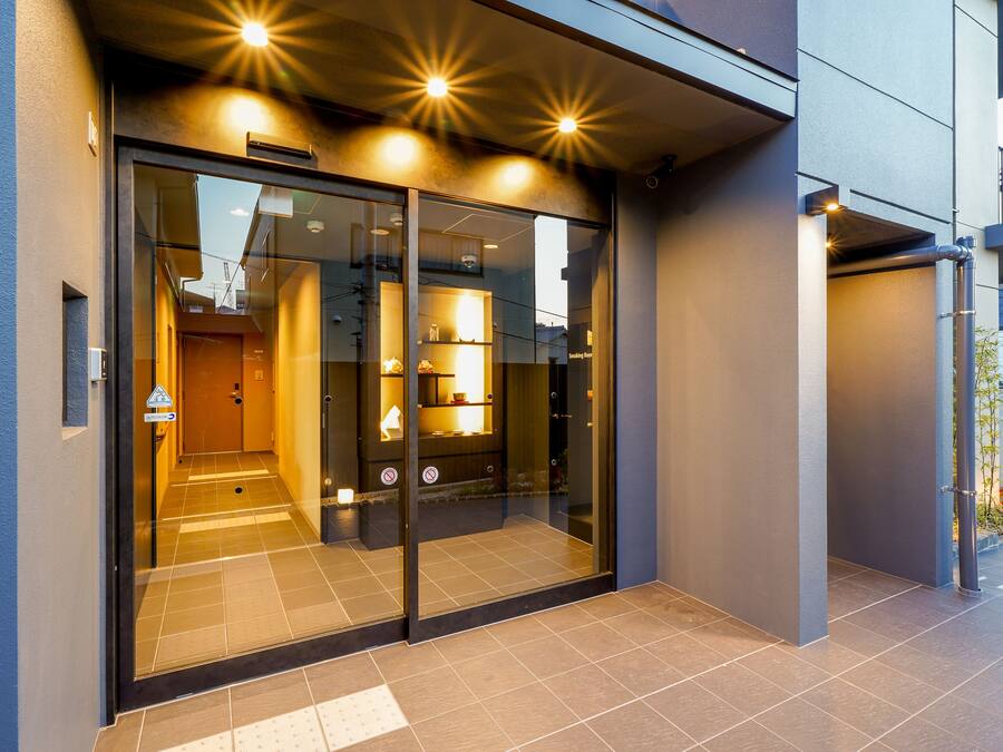 A modern building entrance with glass doors, a visible interior with a reception area, and a tiled floor.
