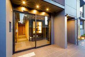 A modern building entrance with glass doors, a visible interior with a reception area, and a tiled floor. - RESI STAY Gojozaka (Kyoto)