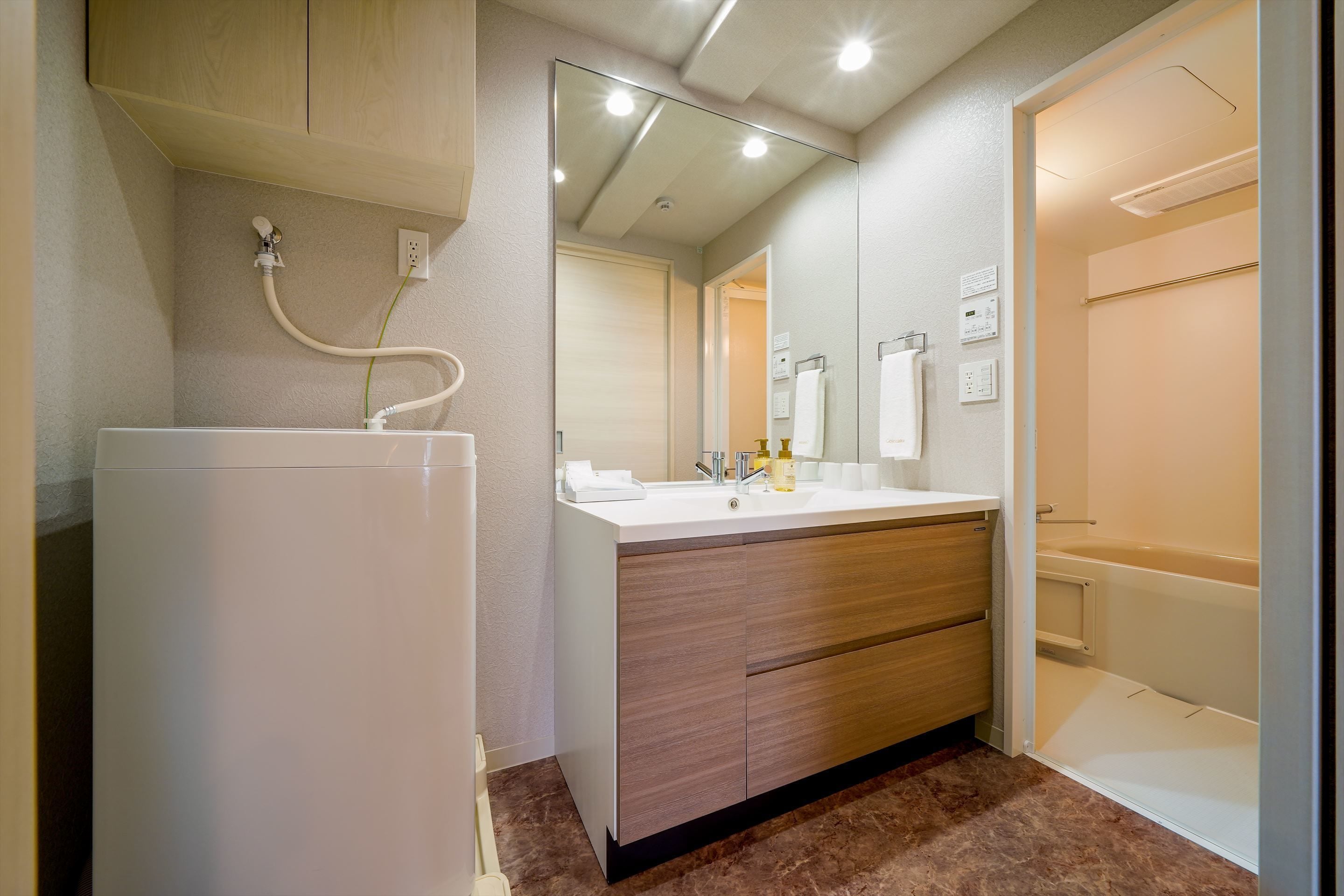 Een moderne badkamer met een wit wastafelmeubel, houten kast en een spiegel.