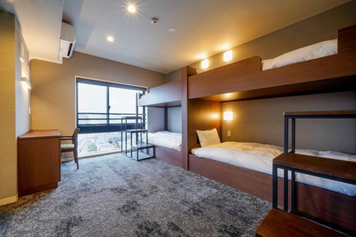 A compact room with bunk beds, a desk, and a window providing a view.