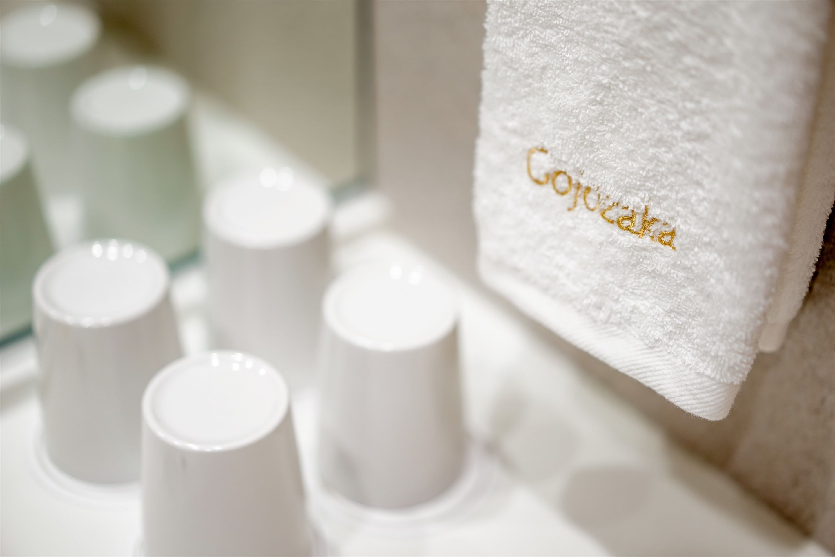 A bathroom with white towels and a towel rack labeled "Cojucara."