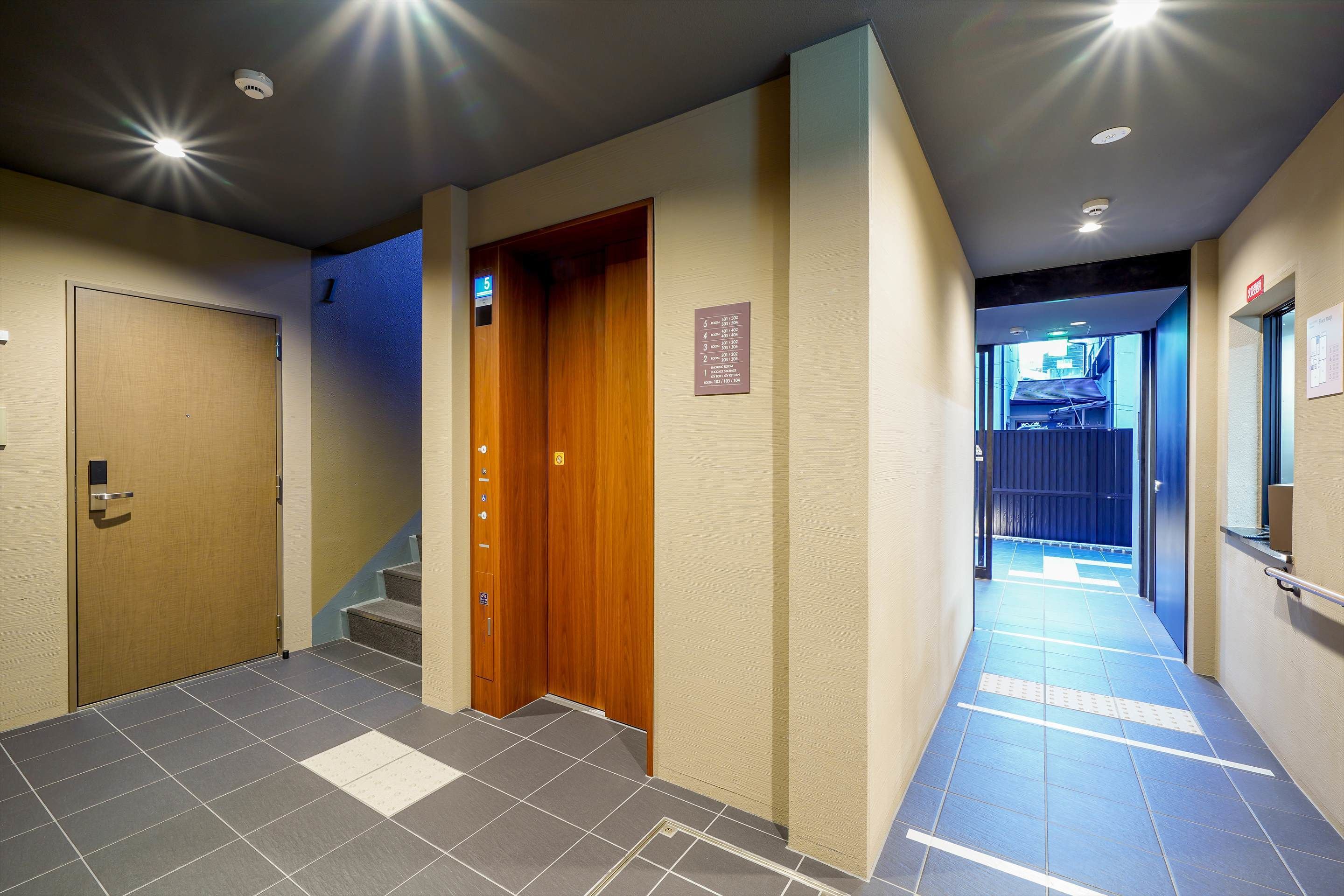 Corredor de hotel com porta de madeira, parede azul e placa indicando o andar.
