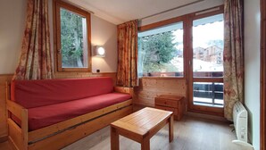 A cozy room with a wooden sofa, a small table, and two windows with curtains. - 27m² studio with balcony, pets allowed, near lifts (Valmorel)