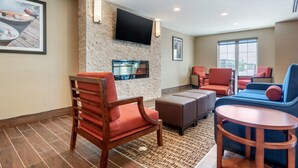 A modern hotel lobby with a stone wall, a flat-screen TV, comfortable seating, and a large window. - Comfort Inn & Suites (Greater Napanee)