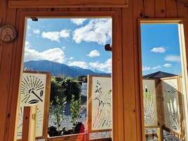 A wooden-framed window with a view of mountains and sky.