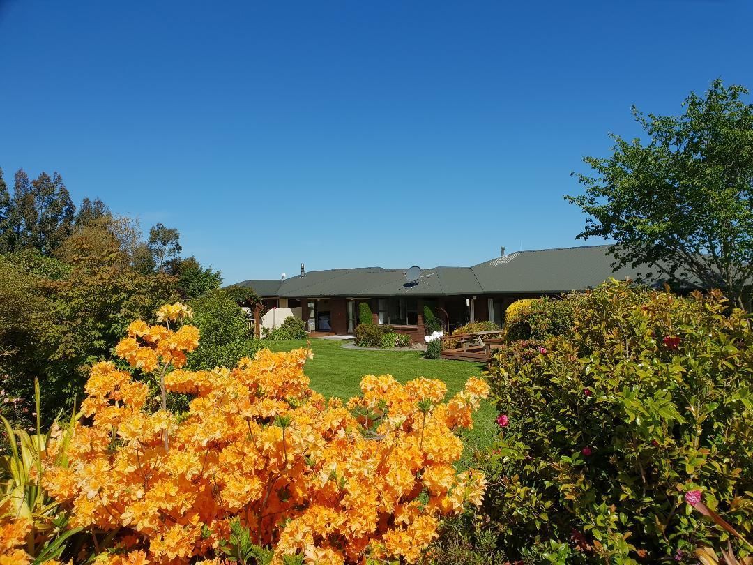 A two-story building with a flat roof, surrounded by well-maintained gardens and trees.