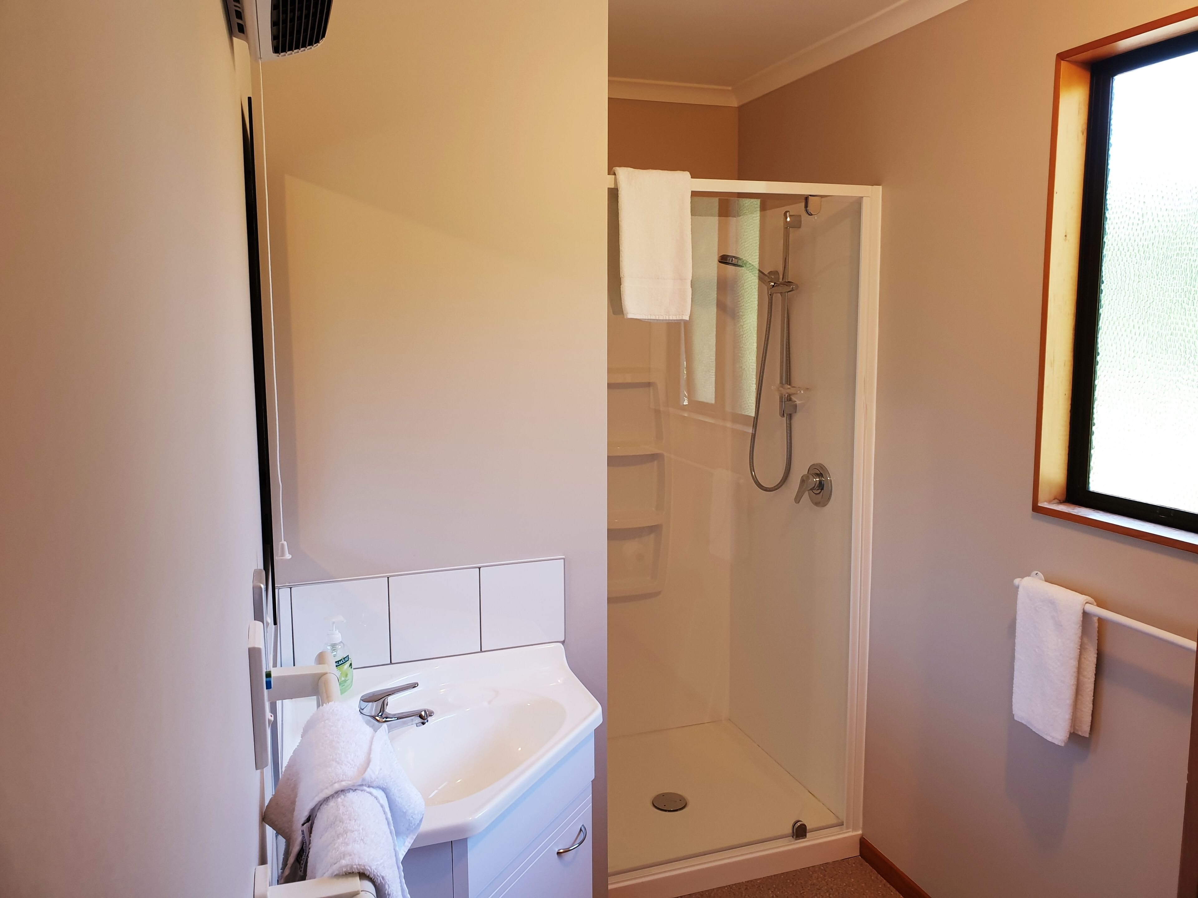 A bathroom with a sink, mirror, and shower.
