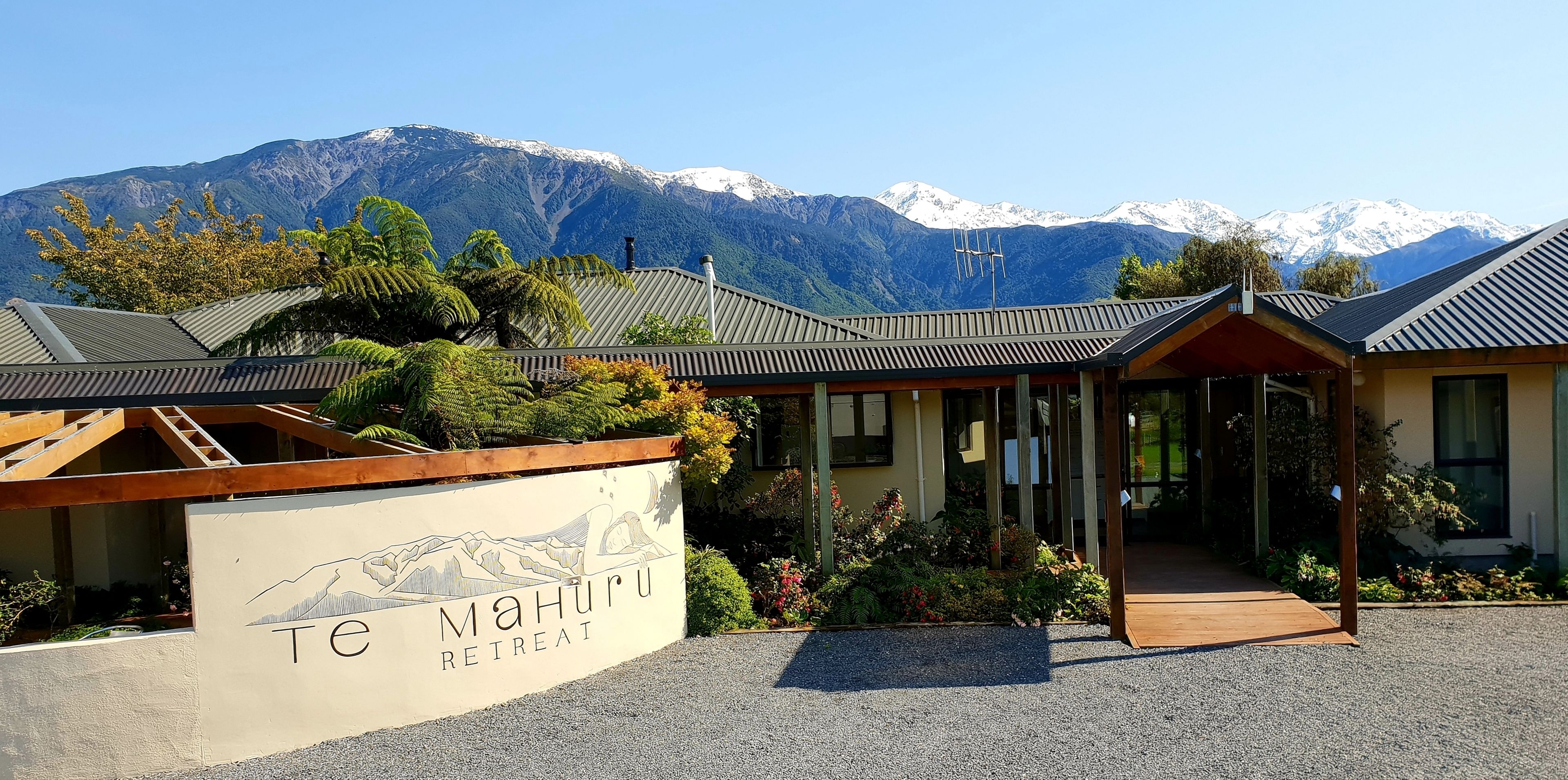 A retreat named "MaHuru" with a mountain view, wooden architecture, and a gravel driveway.
