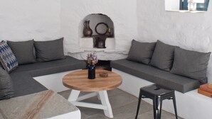 Una sala moderna con chimenea de piedra, una mesa redonda de madera y un sofá gris.