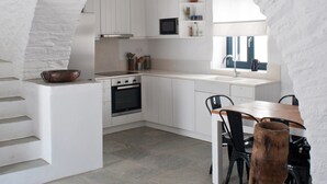 Una cocina moderna con armarios blancos, encimera de piedra y mesa de comedor de madera.