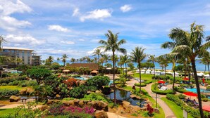 A resort with a pool, palm trees, and a view of the ocean.