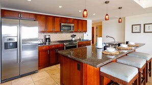 A modern kitchen with wooden cabinets, stainless steel appliances, and a central island with bar stools.