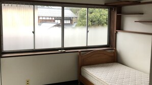 Una habitación con un ventanal grande, una cama de madera y una alfombra estampada.