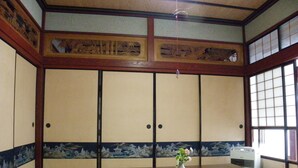 Una habitación japonesa tradicional con suelo de tatami, puertas correderas y una mesa de madera con un jarrón.