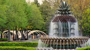 Eine mehrstufige Springbrunnen mit herabfließendem Wasser, umgeben von gepflegten Hecken und blühenden Pflanzen.