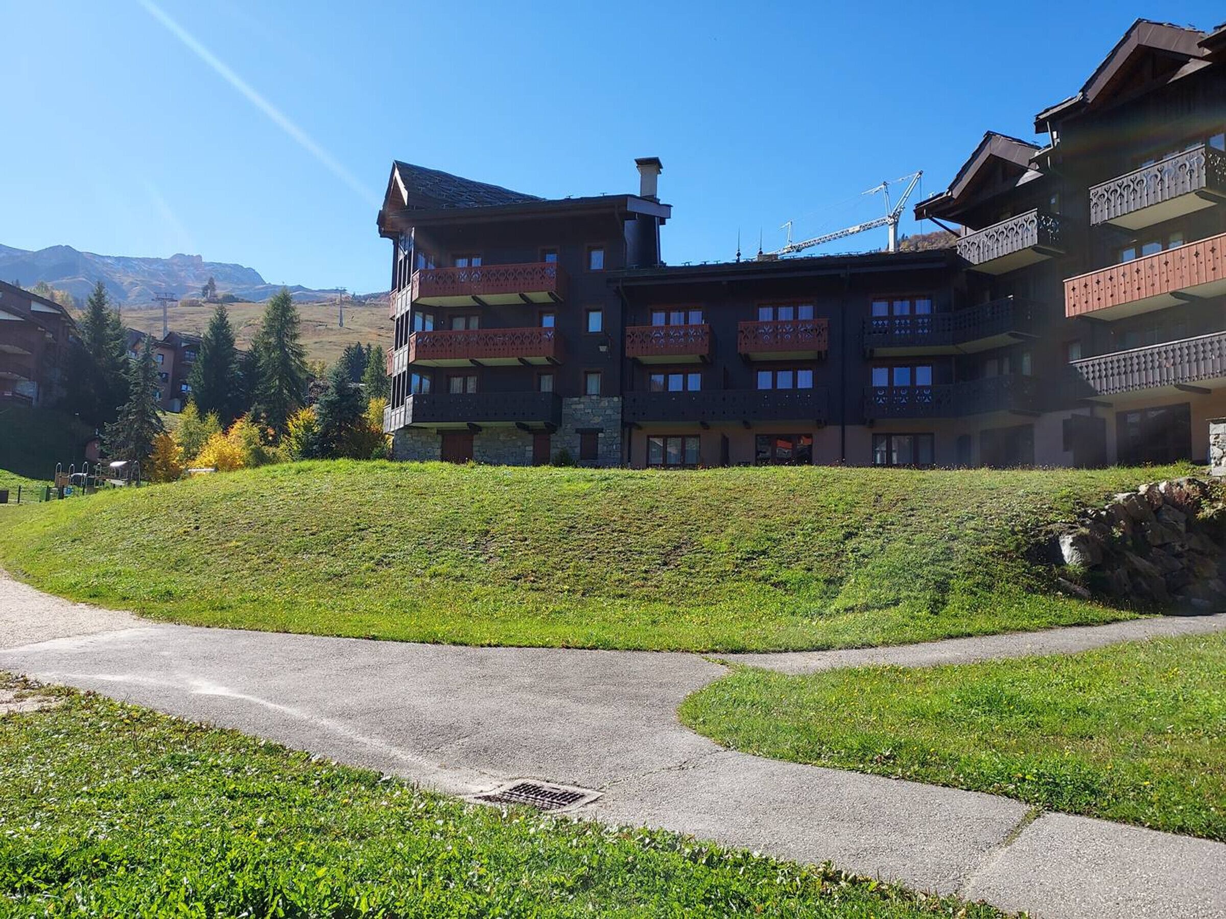 A multi-story hotel with balconies and a ski lift in the background.