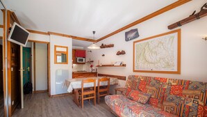 A compact living space with a dining area, kitchenette, and a sofa. - Divisible studio, near slopes and shops, south terrace (Valmorel)