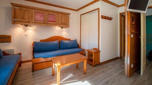 A cozy room with a wooden sofa, a wooden table, and a TV on a stand. - Divisible studio, near slopes and shops, south terrace (Valmorel)